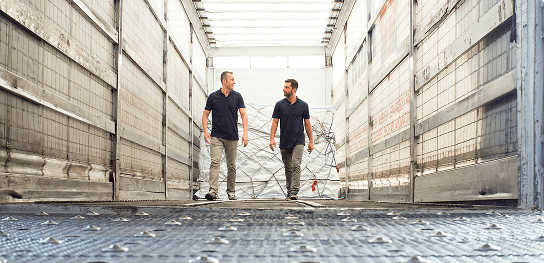 Two men walking down a long aisle discussing logistics